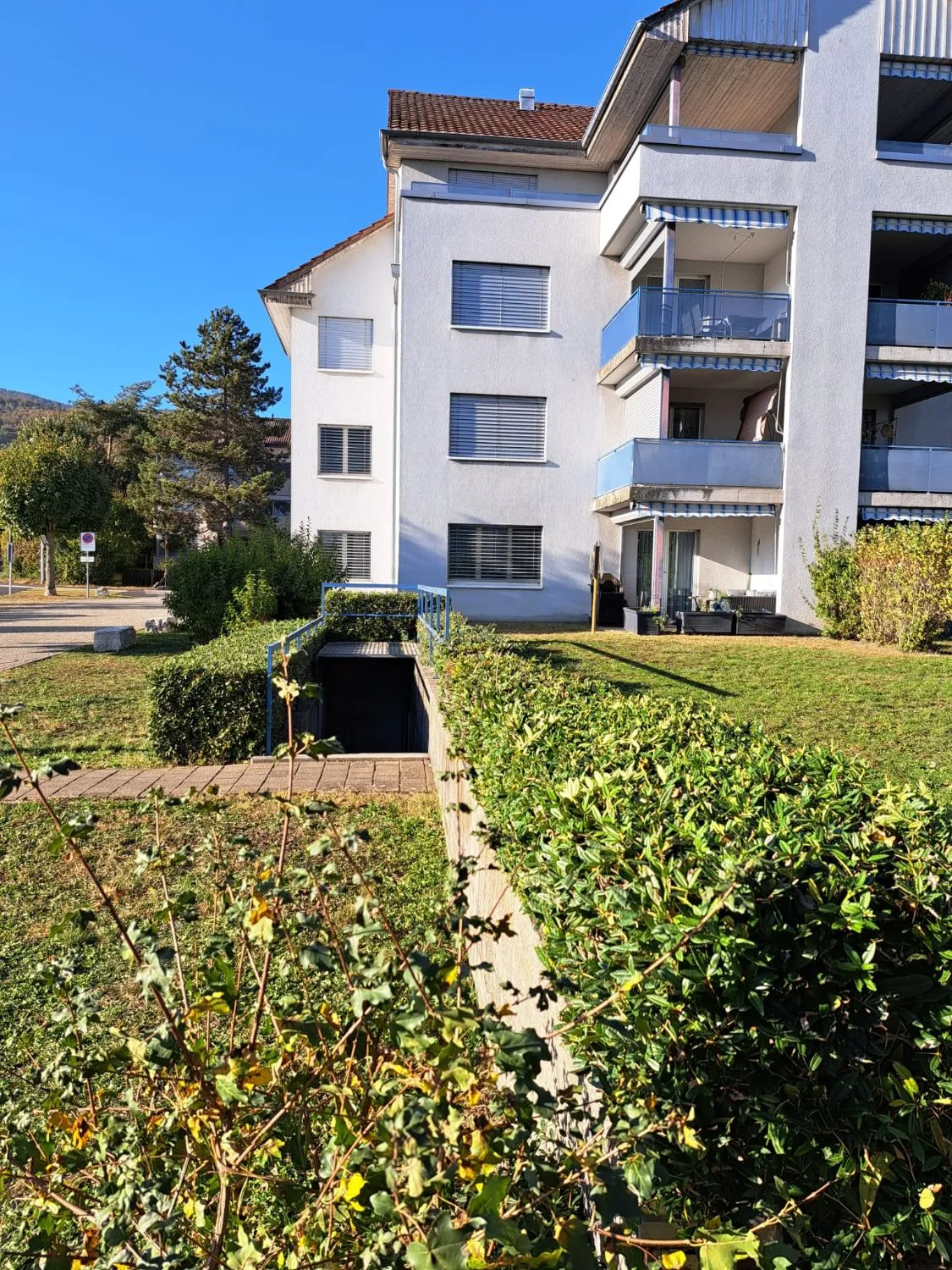 Mehrfamilienhaus mit gepflegten Hecken und Rasenflächen